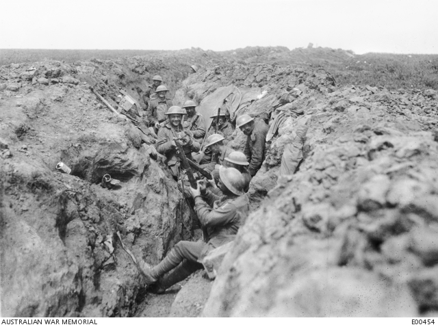 Australian soldiers crowded into a newly captured trench, bayonets fixed, the churned ground of the battlefield visible beyond the parapet.