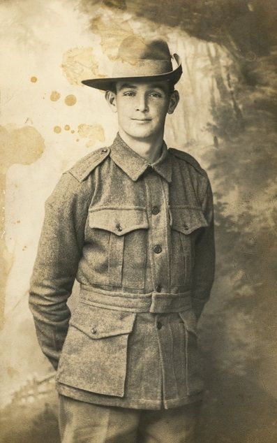 A young soldier in Australian Imperial Force uniform and slouch hat, seated for a studio portrait.