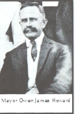 Half-tone studio portrait of a middle-aged man with a heavy moustache, in a three-piece suit and tie, seated against a plain background.