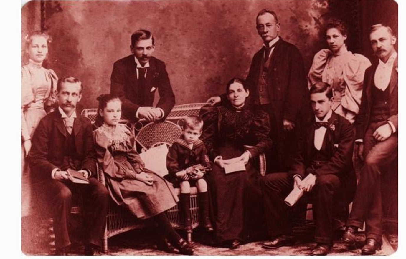 Sepia studio group photograph of ten people — an older seated couple surrounded by grown sons and daughters and one small boy in a sailor suit.